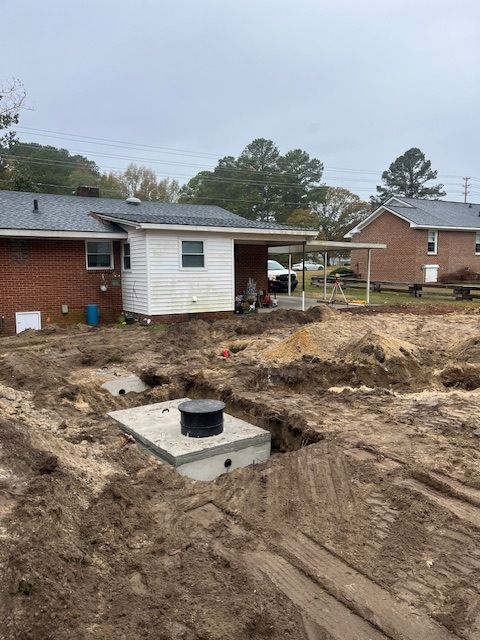 A septic tank is being installed in front of a brick house.