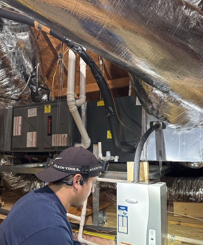 A man wearing a nike hat is working on an air conditioner