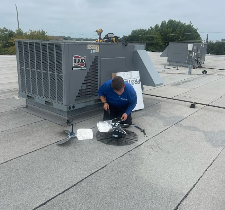 A man is working on an air conditioner on the roof