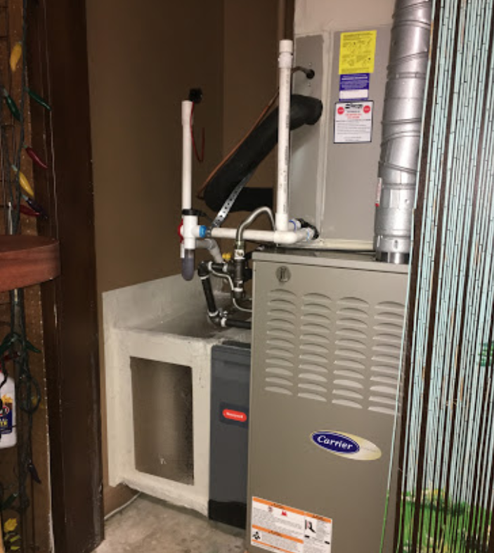 A carrier air conditioner is sitting in a room next to a sink.