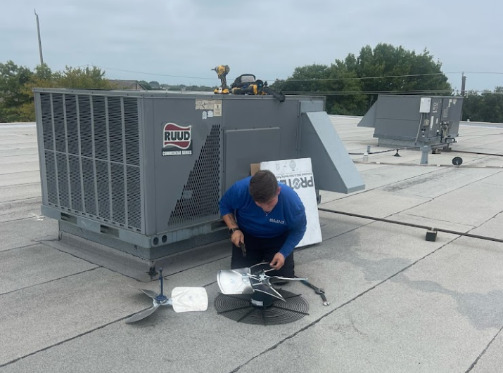 A man is working on an air conditioner on the roof