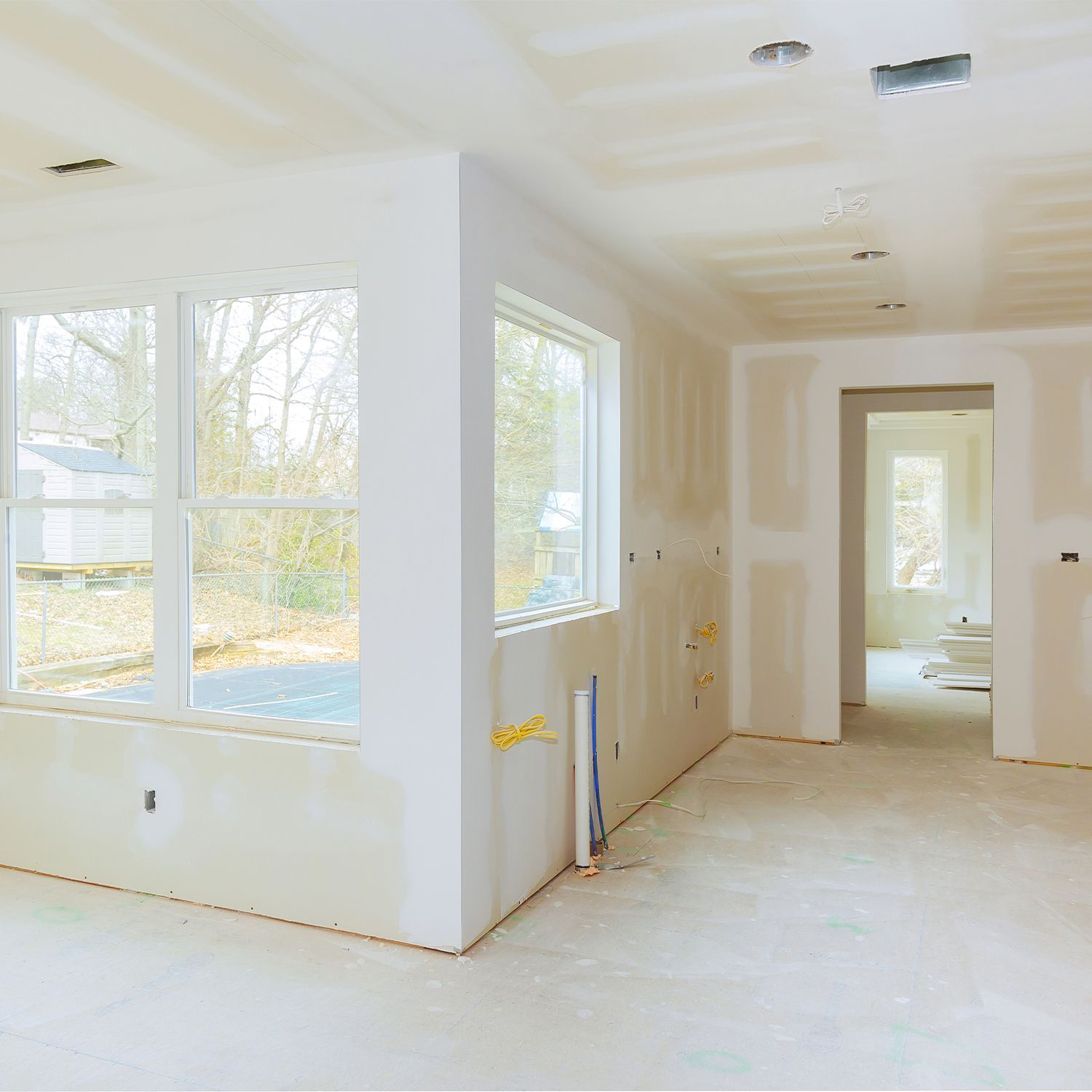 Habitación interior en construcción con paredes de drywall y piso de concreto sin terminar.