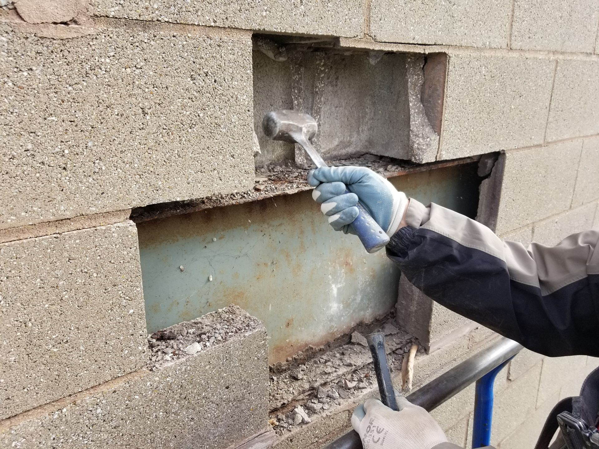 Stonemason replacing stone on a wall that has water damage underneath - a big concern