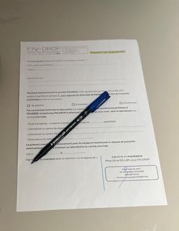 Un médecin, stéthoscope autour du cou, tient et montre un formulaire de « bon de transport » à son bureau.