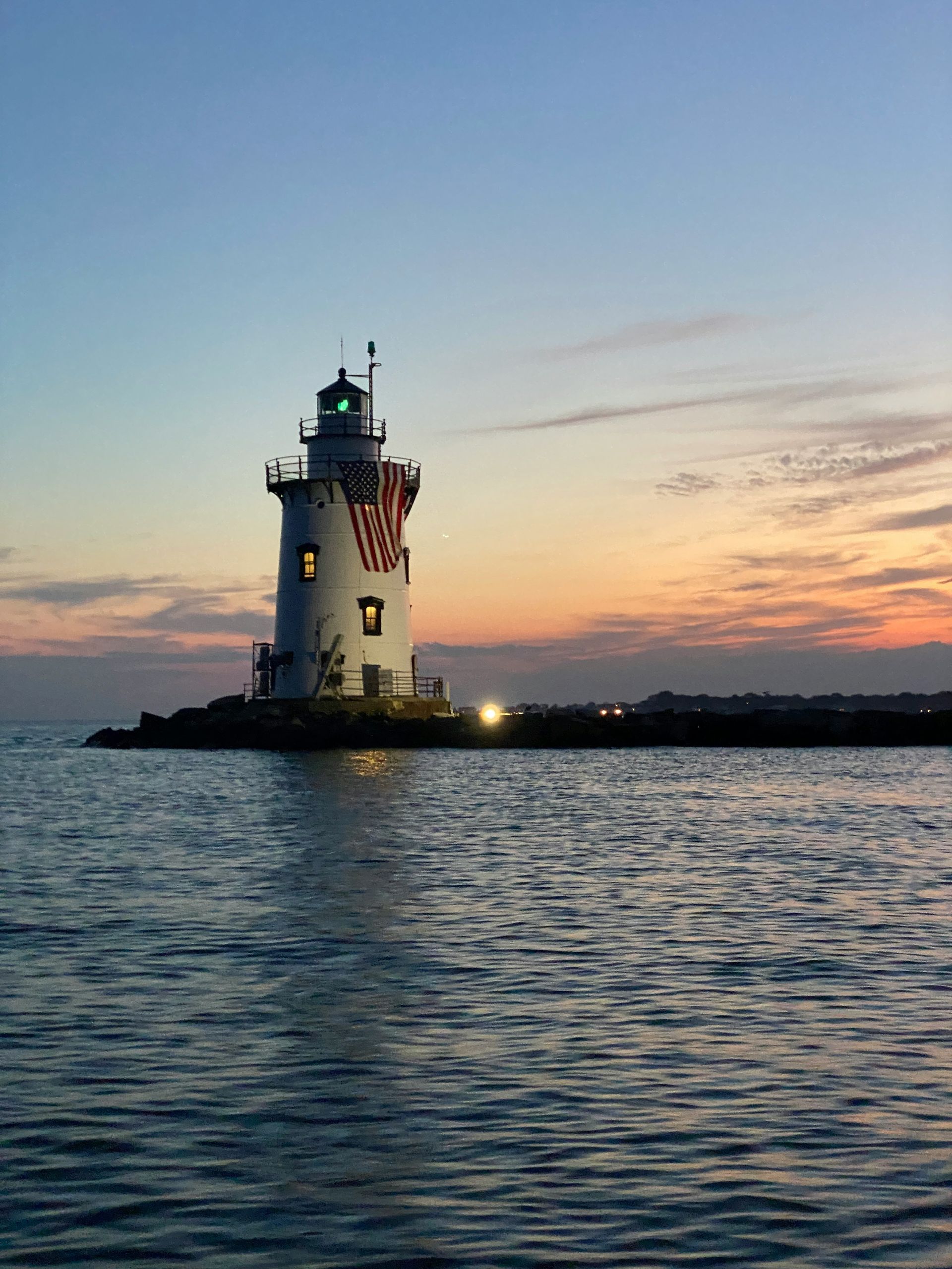 A lighthouse in the middle of a body of water at sunset