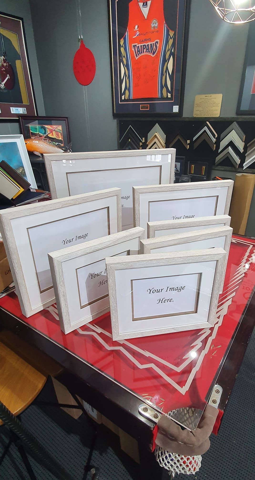 Various White Picture Frames on a Red Table in a Store — Tropical North Framing Gallery Cairns in Bungalow, QLD