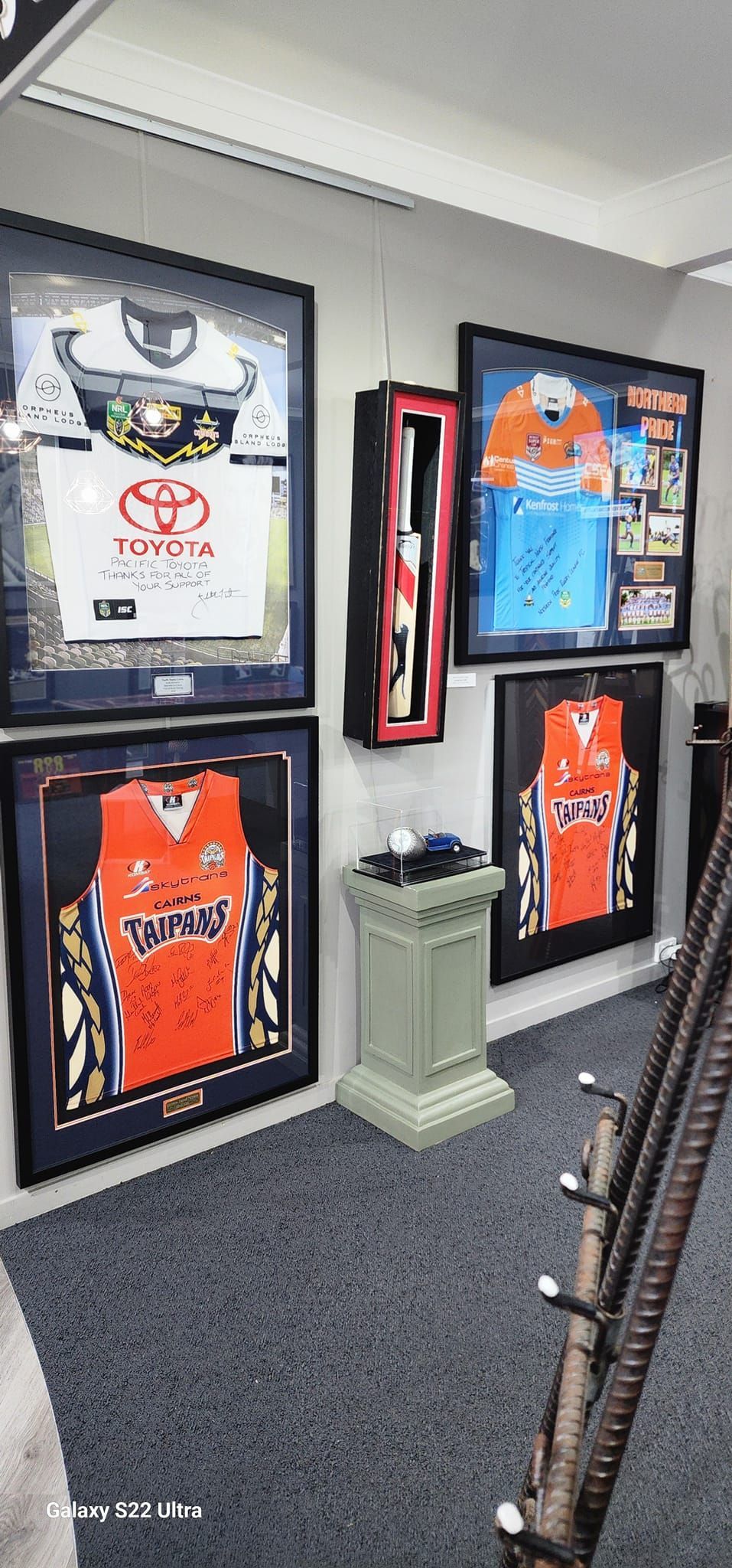 Wall With Framed Sports Jerseys, a Column, and a Decorative Rod — Tropical North Framing Gallery Cairns in Cairns, QLD