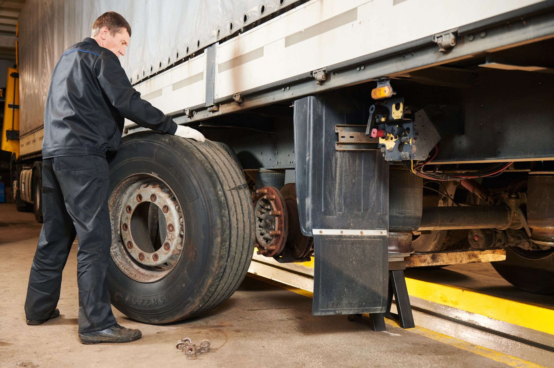 Mechanic changing a tire on a large truck in a repair shop.