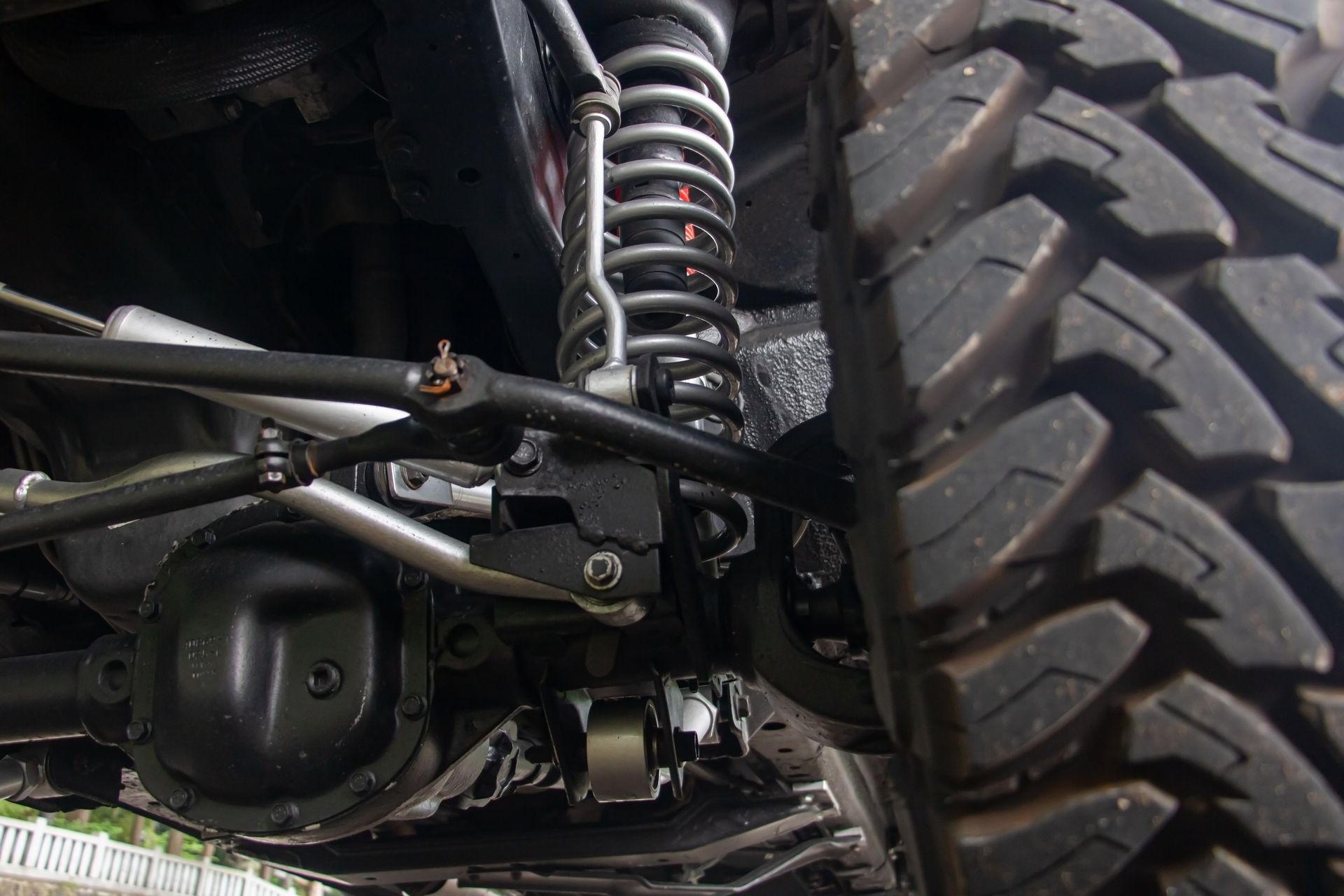 Underside view of a black off-road vehicle's suspension system with a large tire and coil-over shock absorber. Underside view of a black off-road vehicle's suspension system with a large tire and coil-over shock absorber.