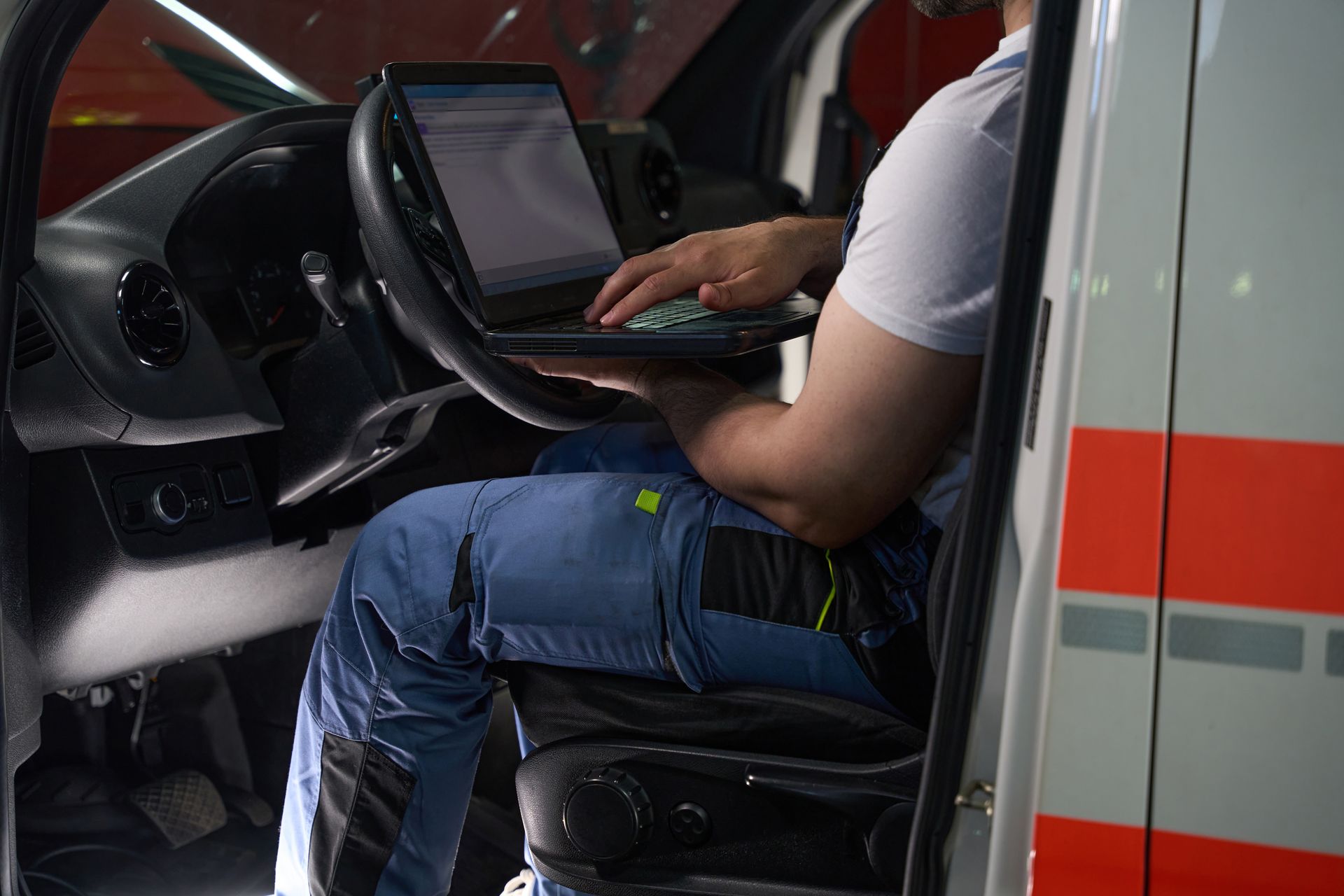 Person in ambulance using a laptop, parked.