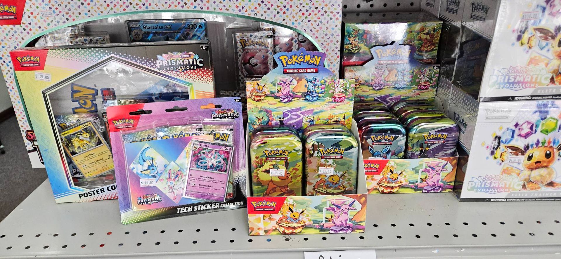 A bunch of pokemon cards are sitting on a shelf in a store.