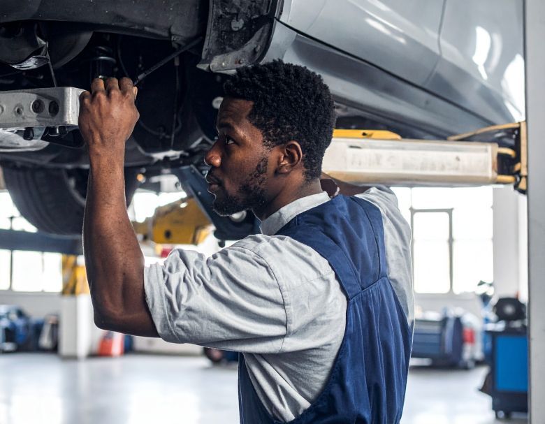 Mechanic working on a car raised on a lift in a repair shop.