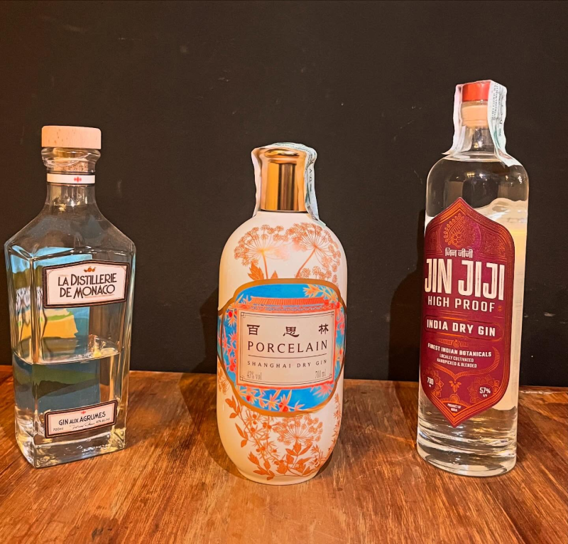 Tre bottiglie di gin su una superficie di legno su uno sfondo scuro: 