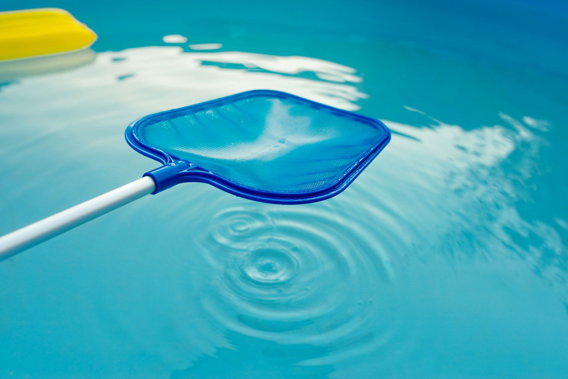 Blue pool skimmer in turquoise water, creating concentric ripples.