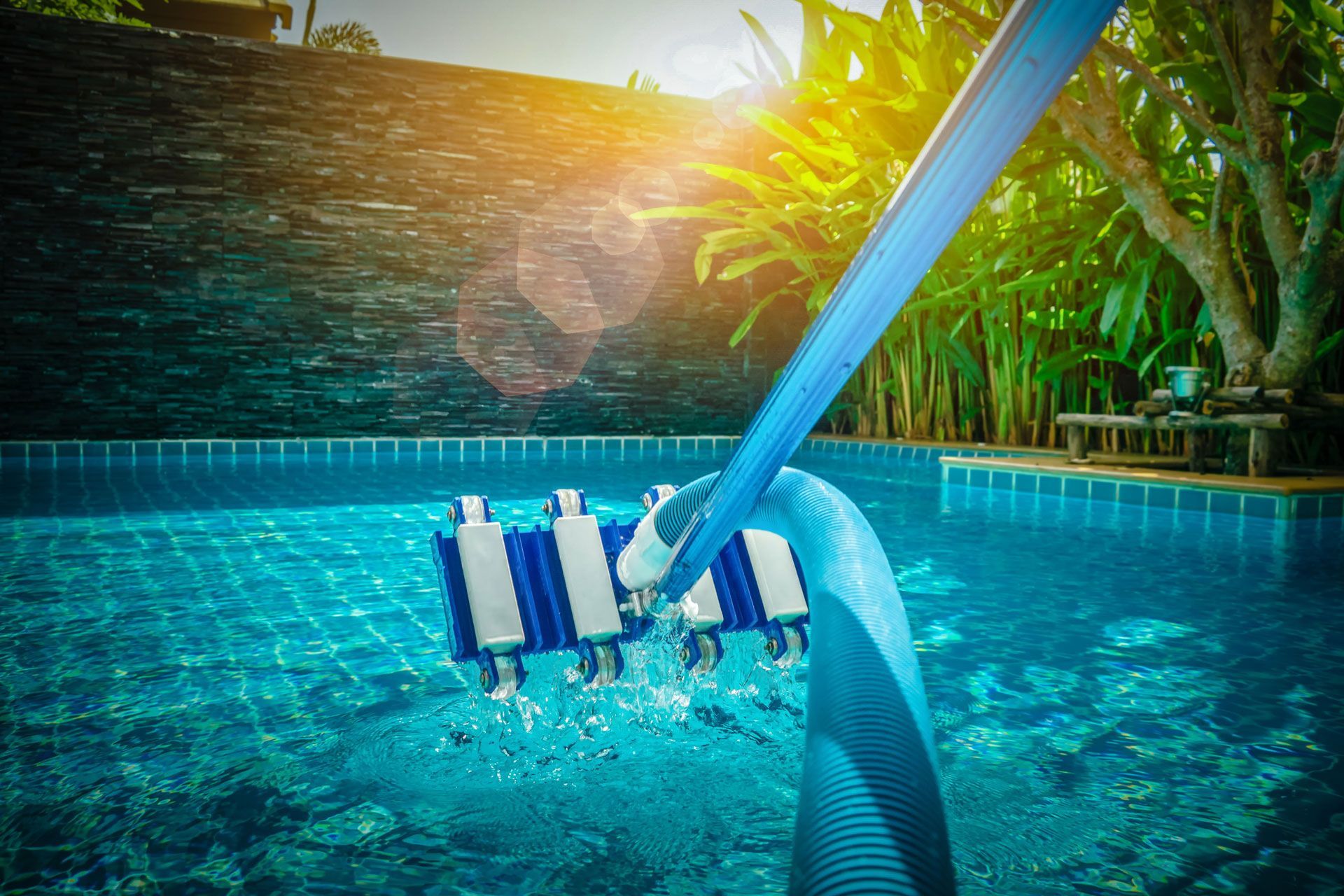 Pool cleaner in a turquoise pool with greenery in the background.