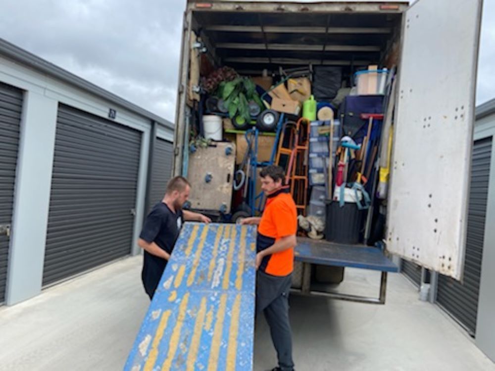 Two Men Are Loading a Truck With a Wooden Ramp — Bellarine Removals In Armstrong Creek, VIC