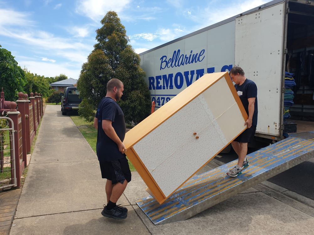Two Men Are Carrying a Large Piece of Furniture Out of a Moving Truck — Bellarine Removals In Bacchus Marsh, VIC