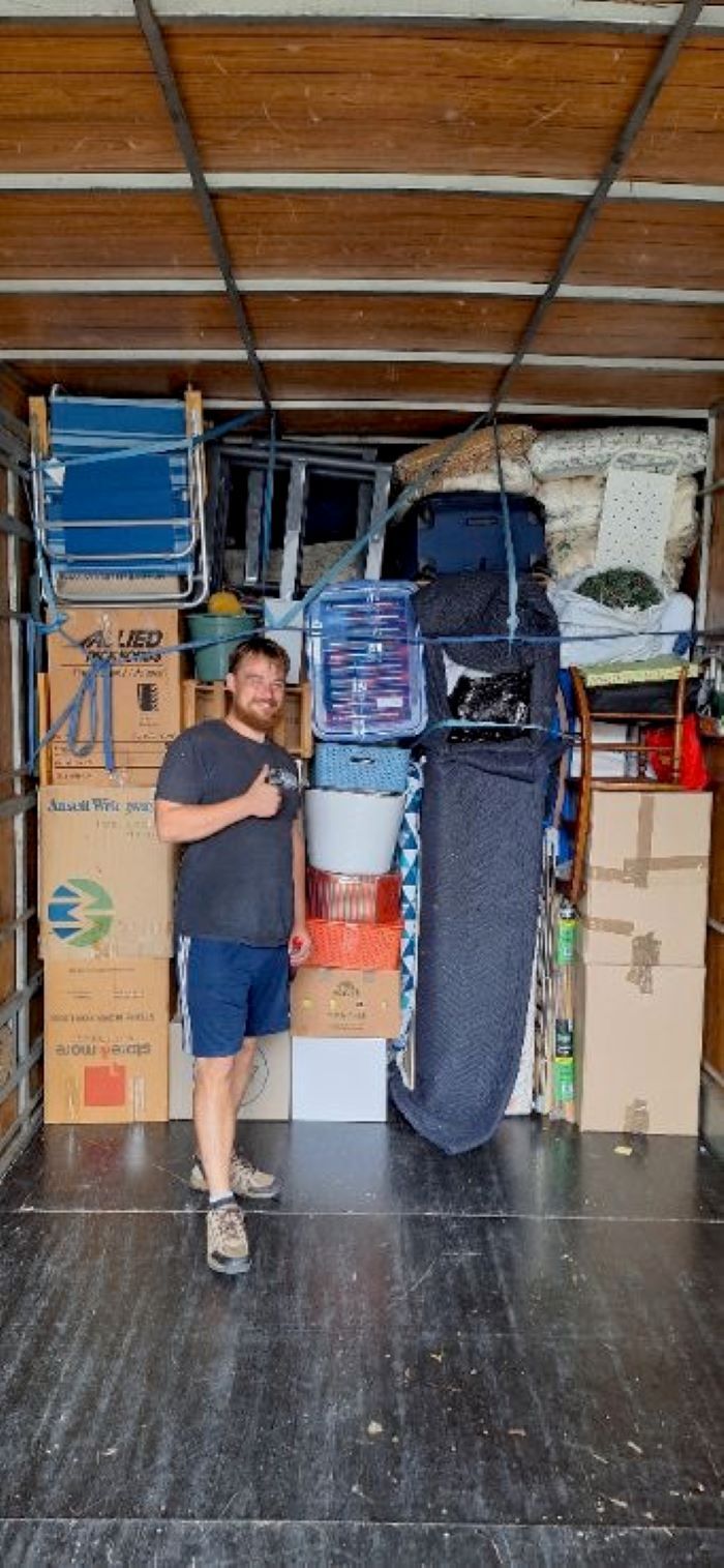 A Man is Standing in the Back of a Truck Filled With Boxes — Bellarine Removals In Bacchus Marsh, VIC