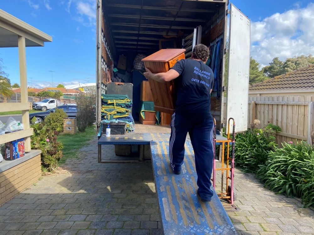 A Man is Loading a Piano Into a Moving Truck — Bellarine Removals In Geelong, VIC