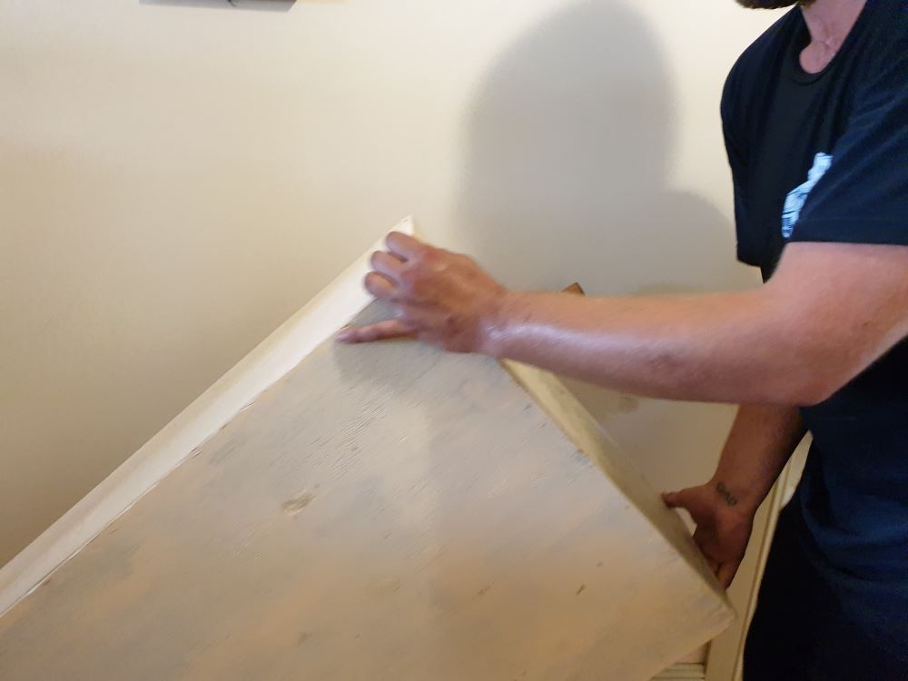 A Man in a Black Shirt is Holding a Piece of Wood — Bellarine Removals In Highton, VIC