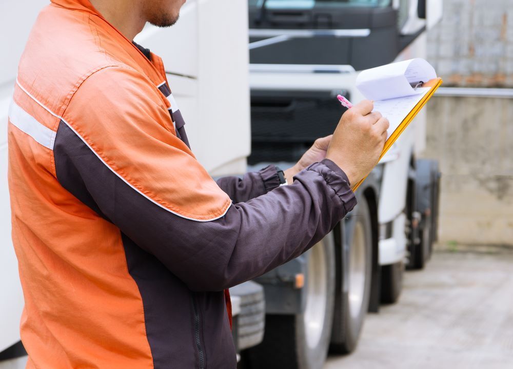 A Man is Writing on a Clipboard in Front of a Truck — Bellarine Removals In Melbourne, VIC