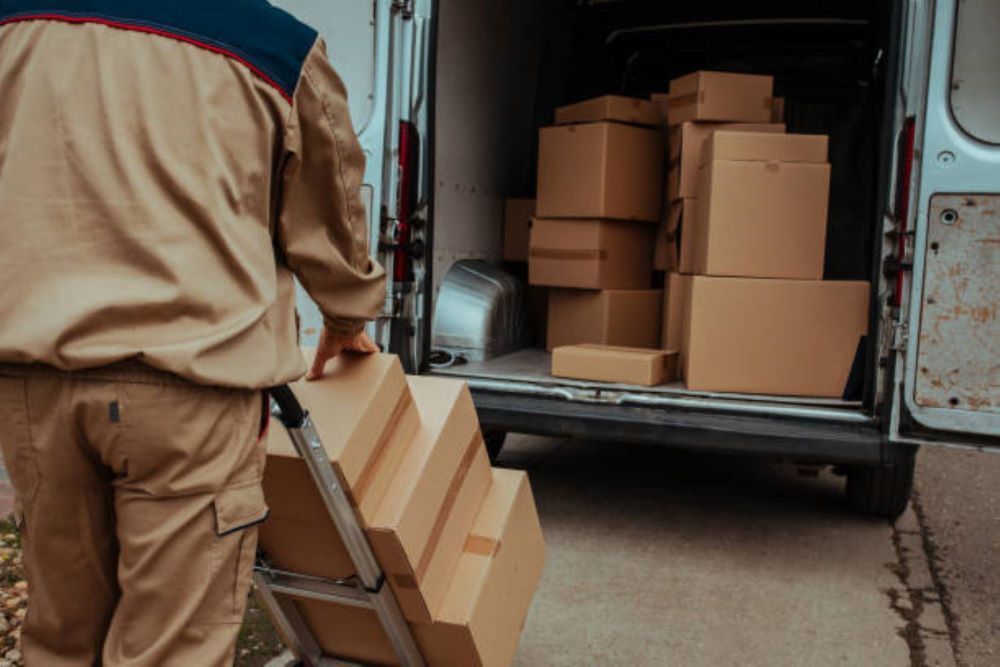 A Delivery Man is Loading Boxes Into a Van — Bellarine Removals In Melton, VIC