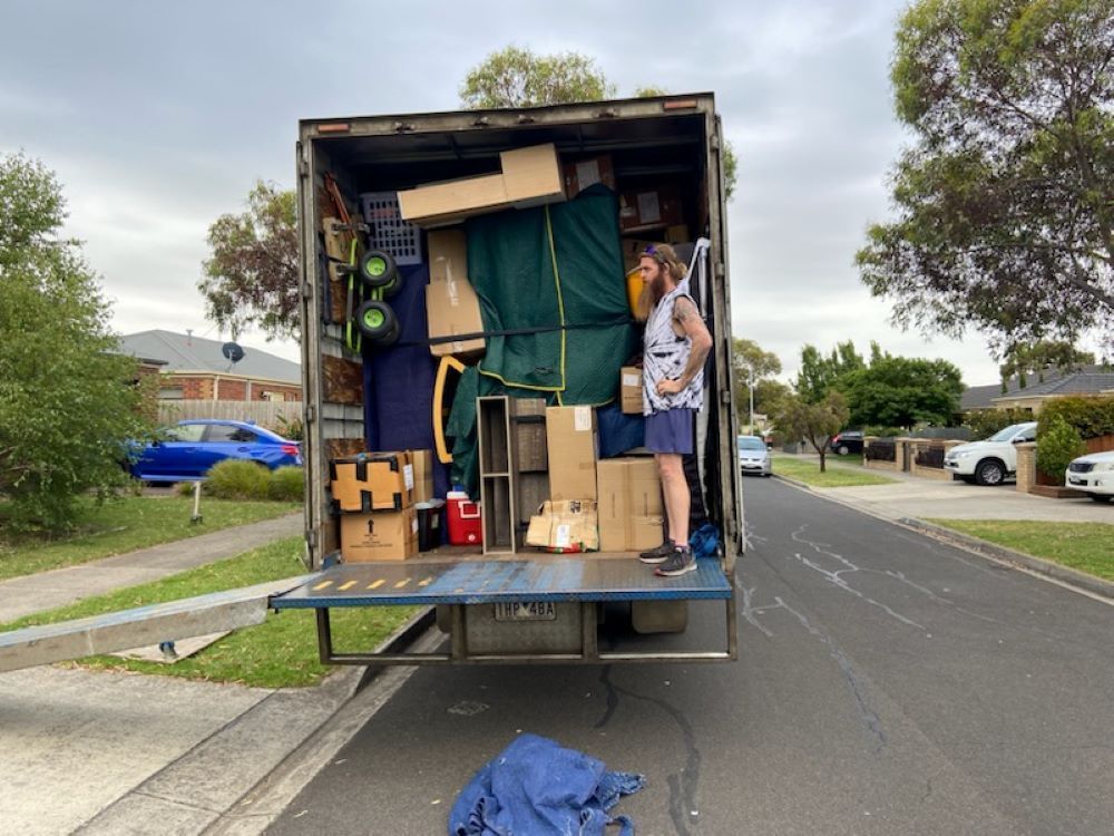 A Man is Standing in the Back of a Truck — Bellarine Removals In Ocean Grove, VIC