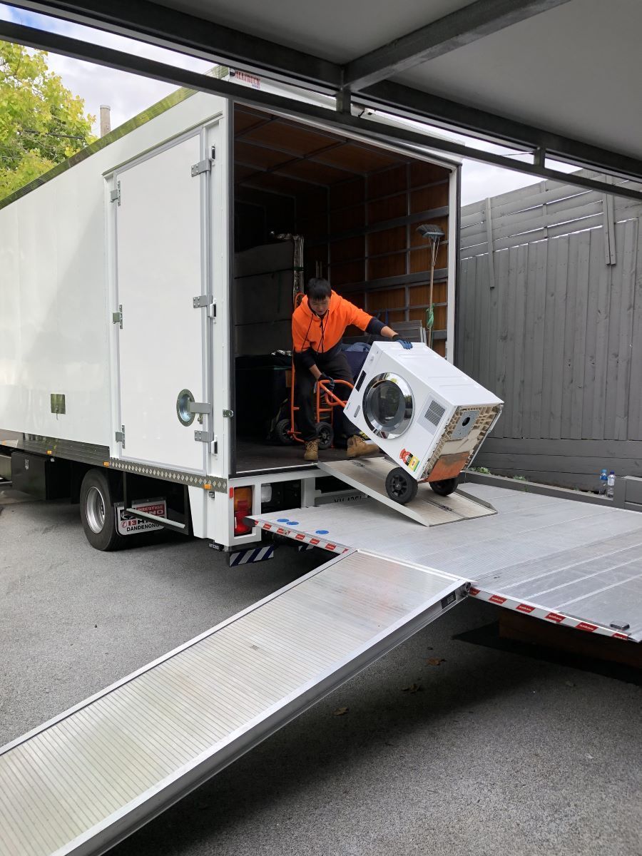 A Man is Loading a Washing Machine Into a Moving Truck — Bellarine Removals In Bellarine Peninsula, VIC