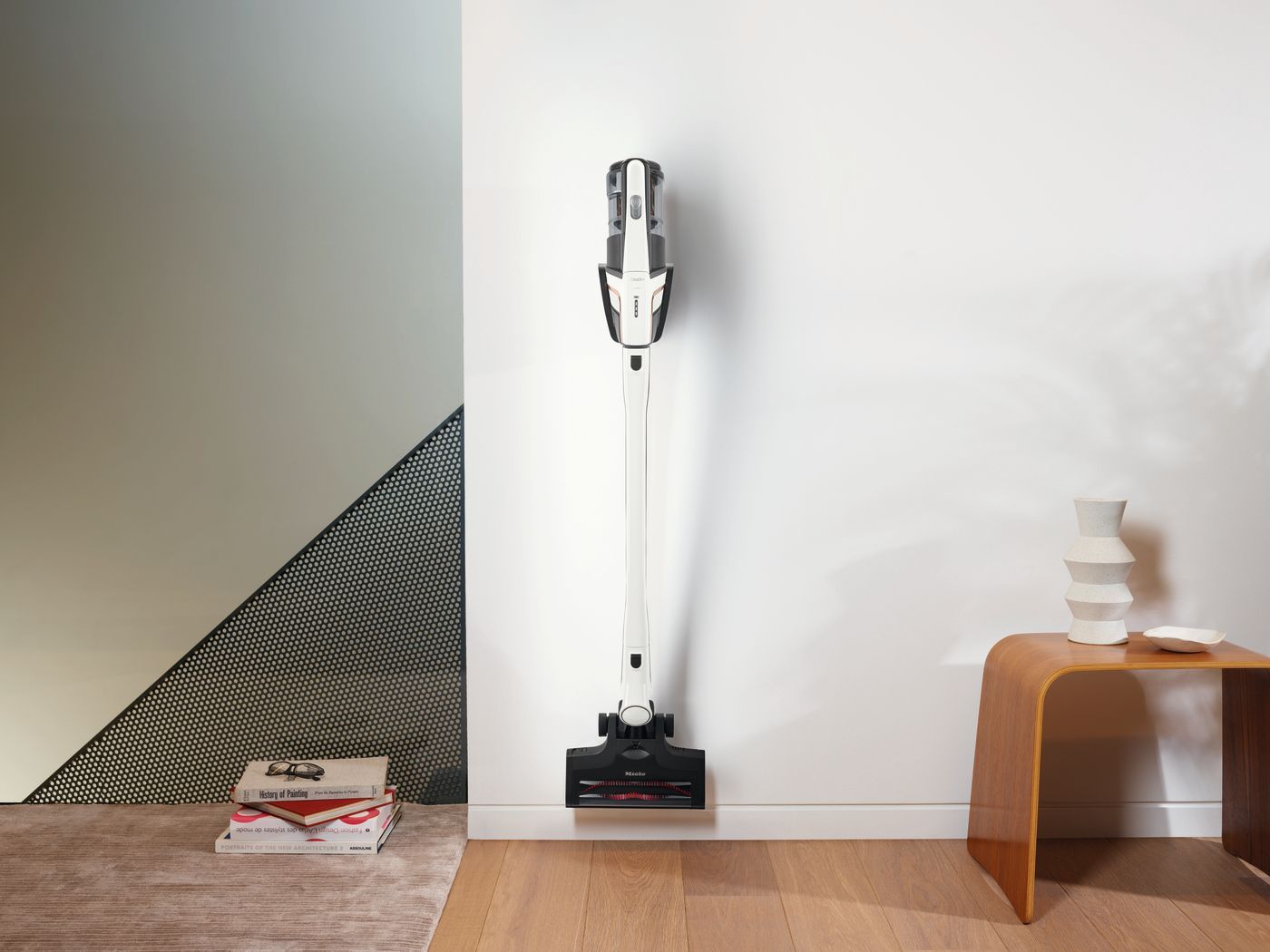 Vacuum cleaner docked on white wall near a small table and patterned wall.