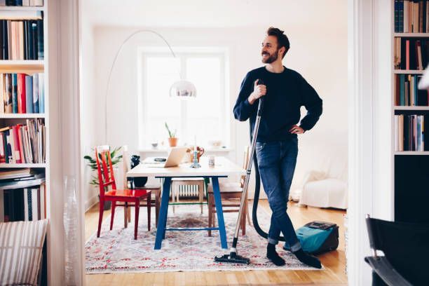 Happy man with a vacuum cleaner in his dining room, showcasing Cape Fear Vacuums as a top vacuum cleaner supplier in Wallace, NC.