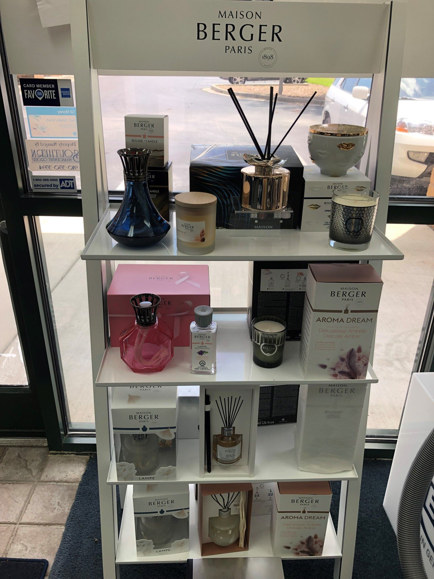 White display shelf with Maison Berger Paris products, including diffusers, candles, and fragrance bottles.