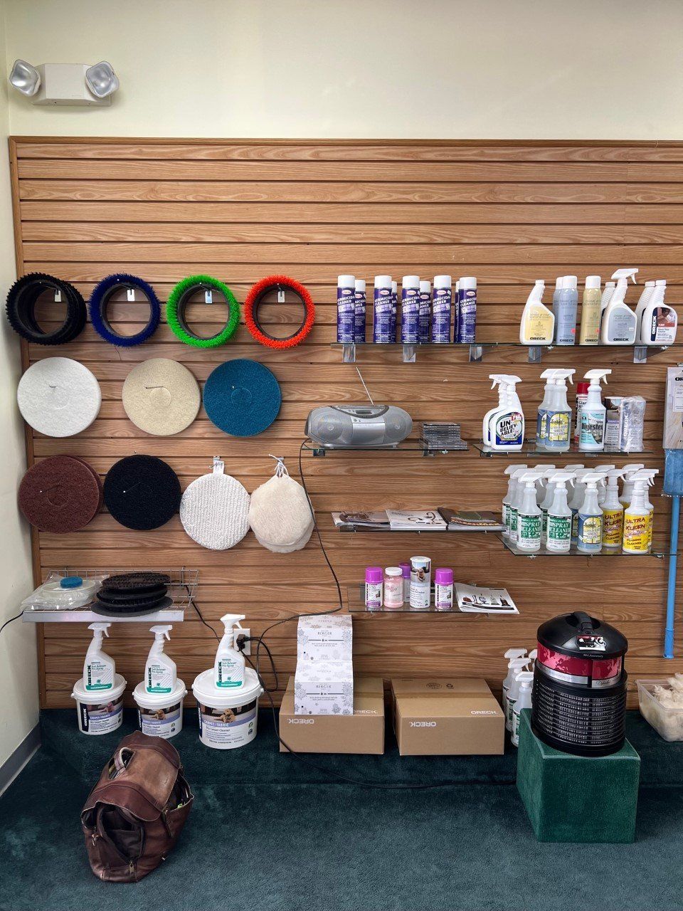 Display of cleaning supplies on shelves in a store. Includes spray bottles, pads, and a vacuum.