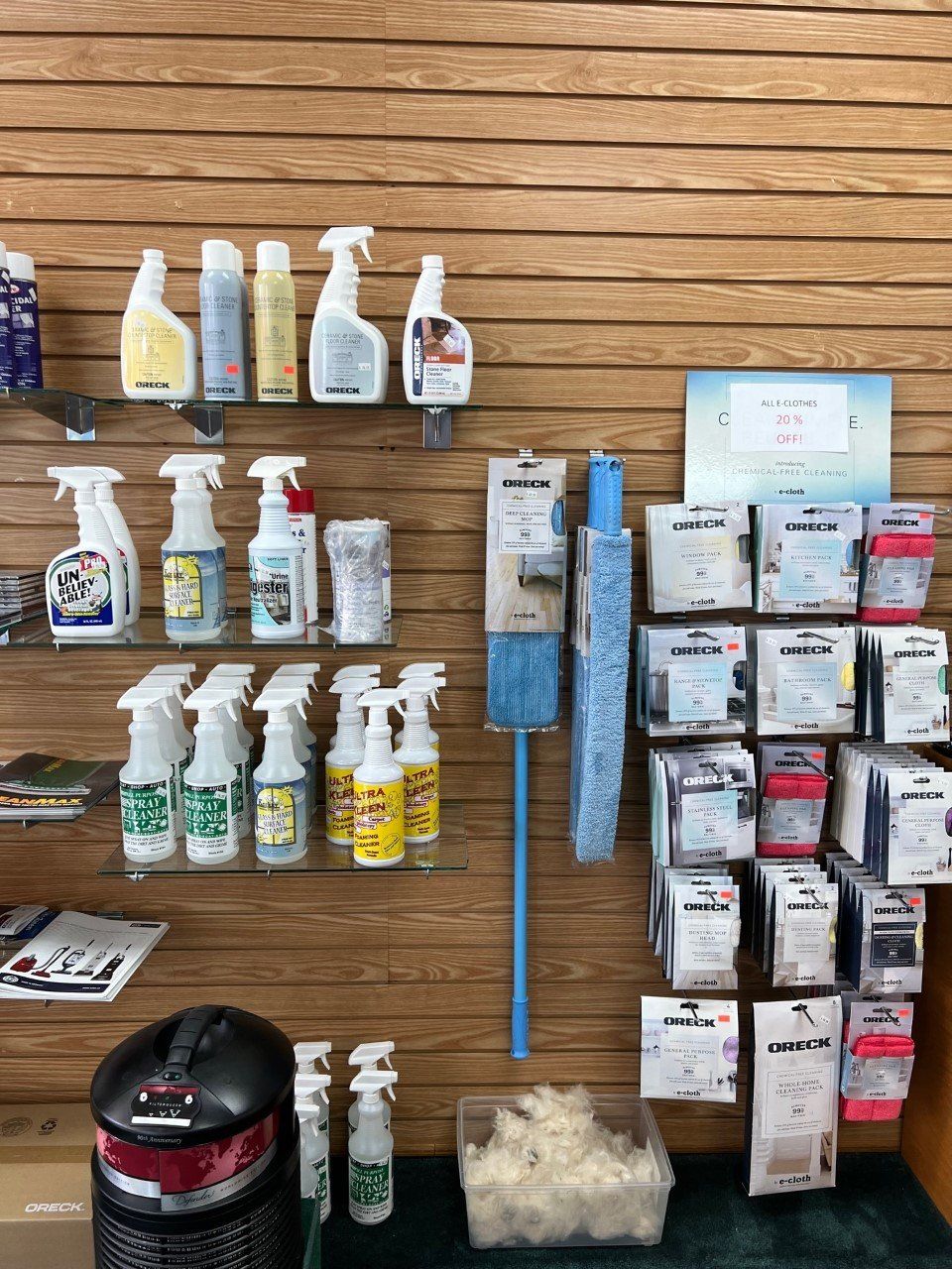 Cleaning products and accessories displayed on wooden slat wall in a store.