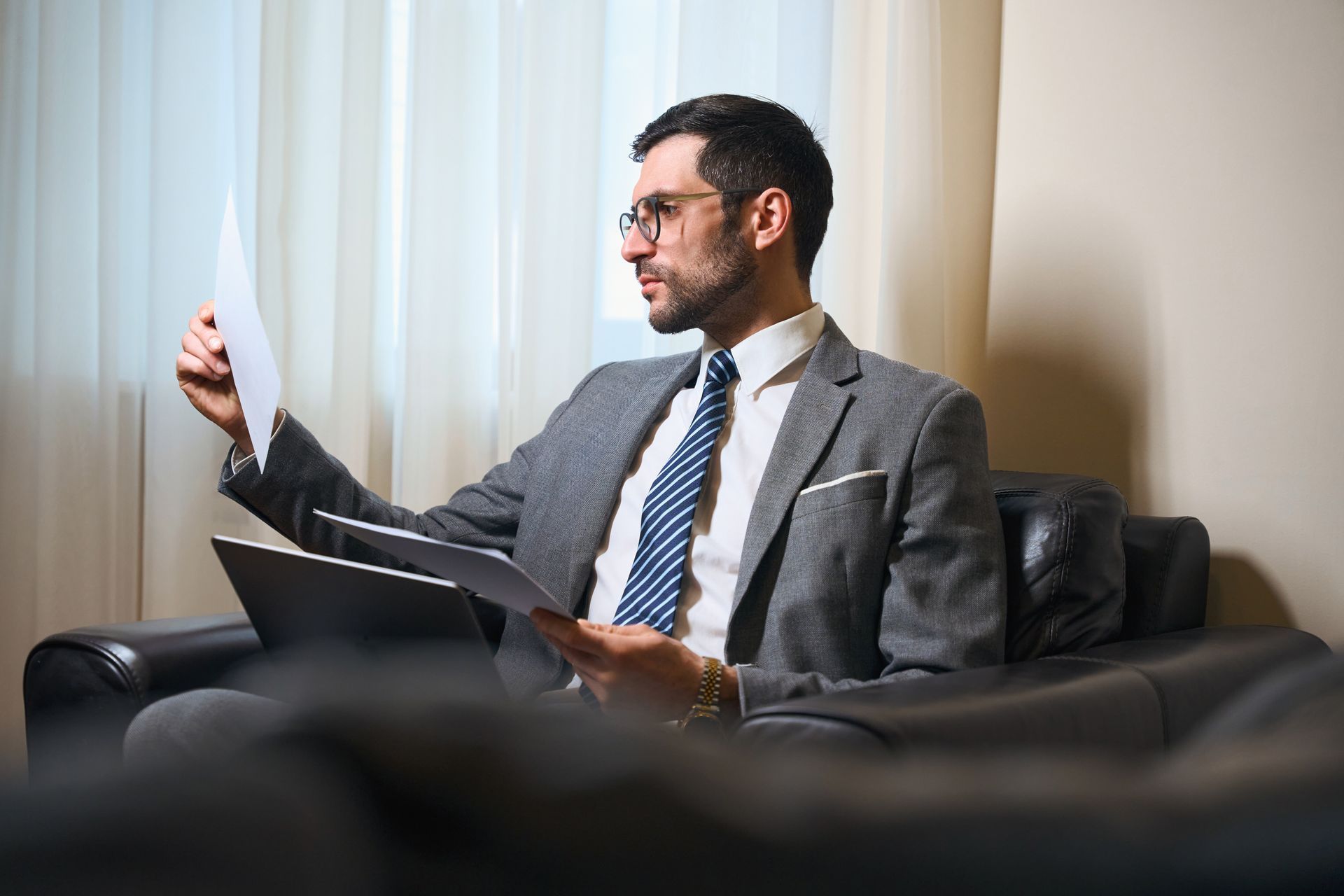 A man in a suit and tie is sitting in a chair holding a piece of paper.