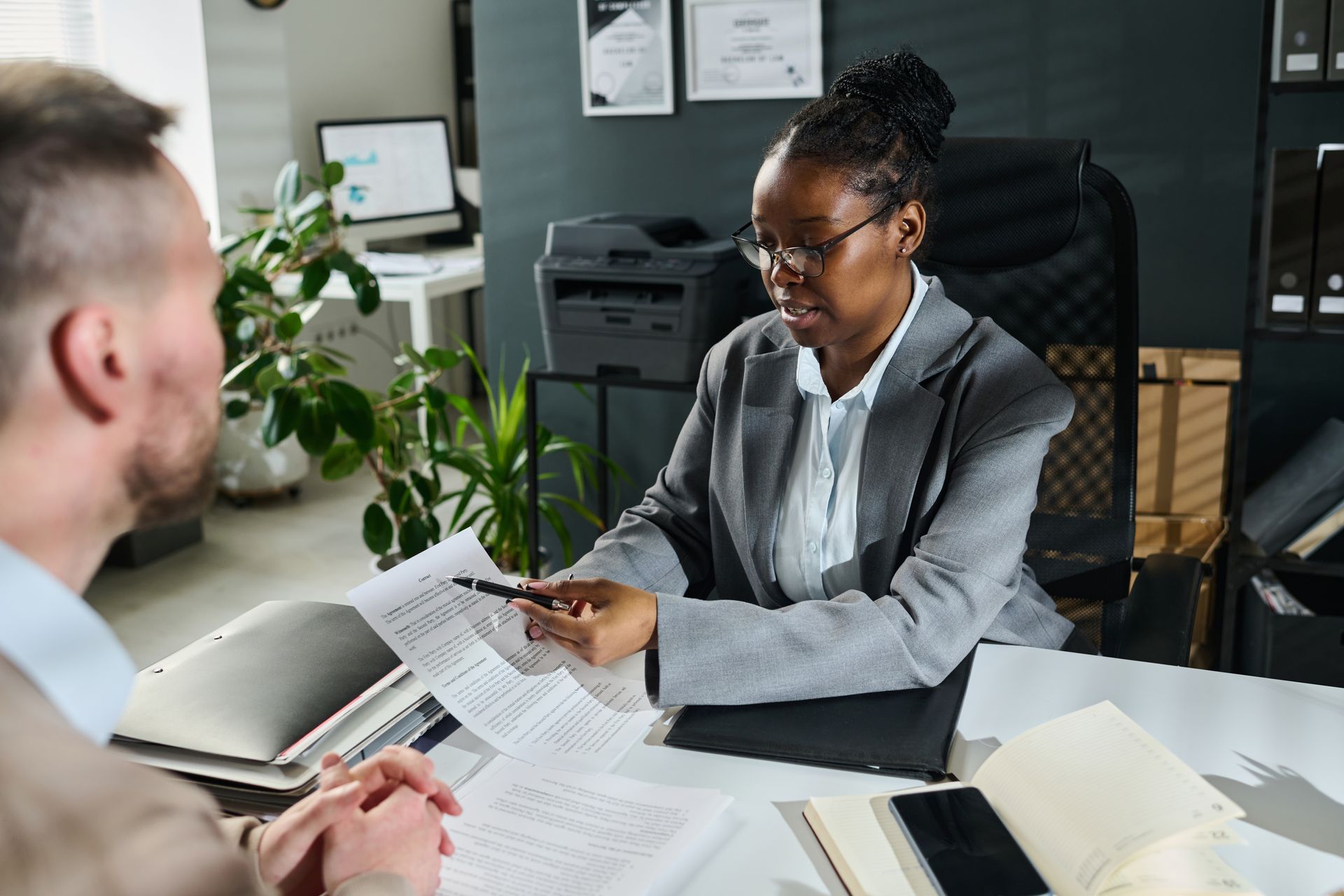 A woman is sitting at a desk talking to a man.