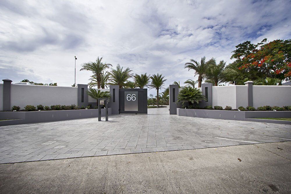 A gated entrance to a house with palm trees in the background