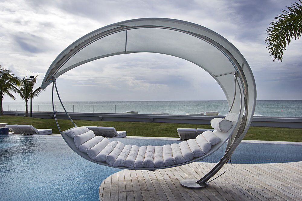 A white chair with a canopy sits next to a swimming pool
