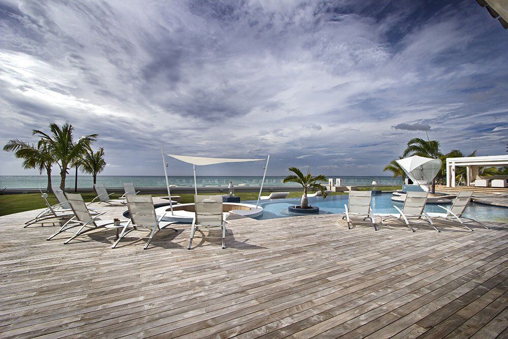 A wooden deck with chairs and umbrellas overlooking the ocean
