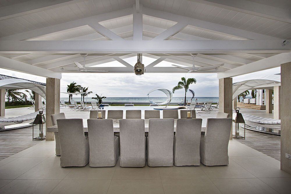 A dining room with a table and chairs and a view of the ocean