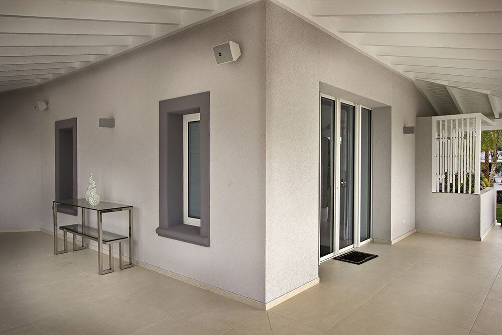 A corner of a house with a table and chairs and a sliding glass door.