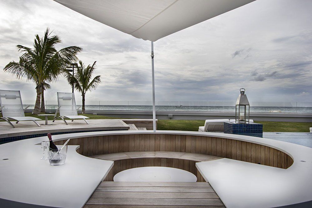 A bucket of champagne sits on a table next to a swimming pool