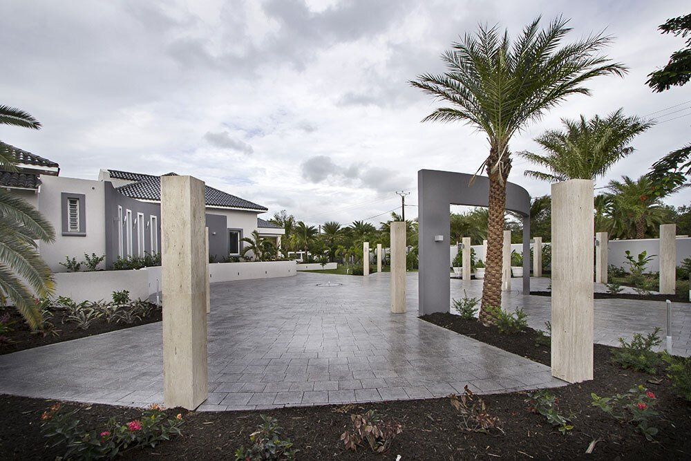A driveway with palm trees in front of a house