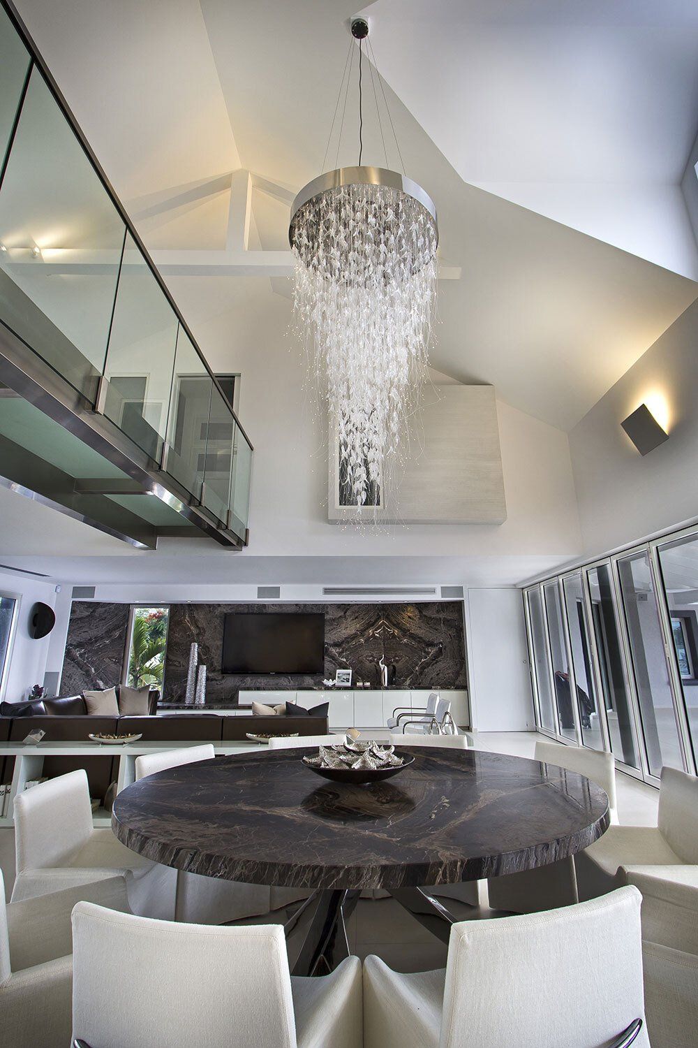 A dining room with a round table and chairs and a chandelier hanging from the ceiling