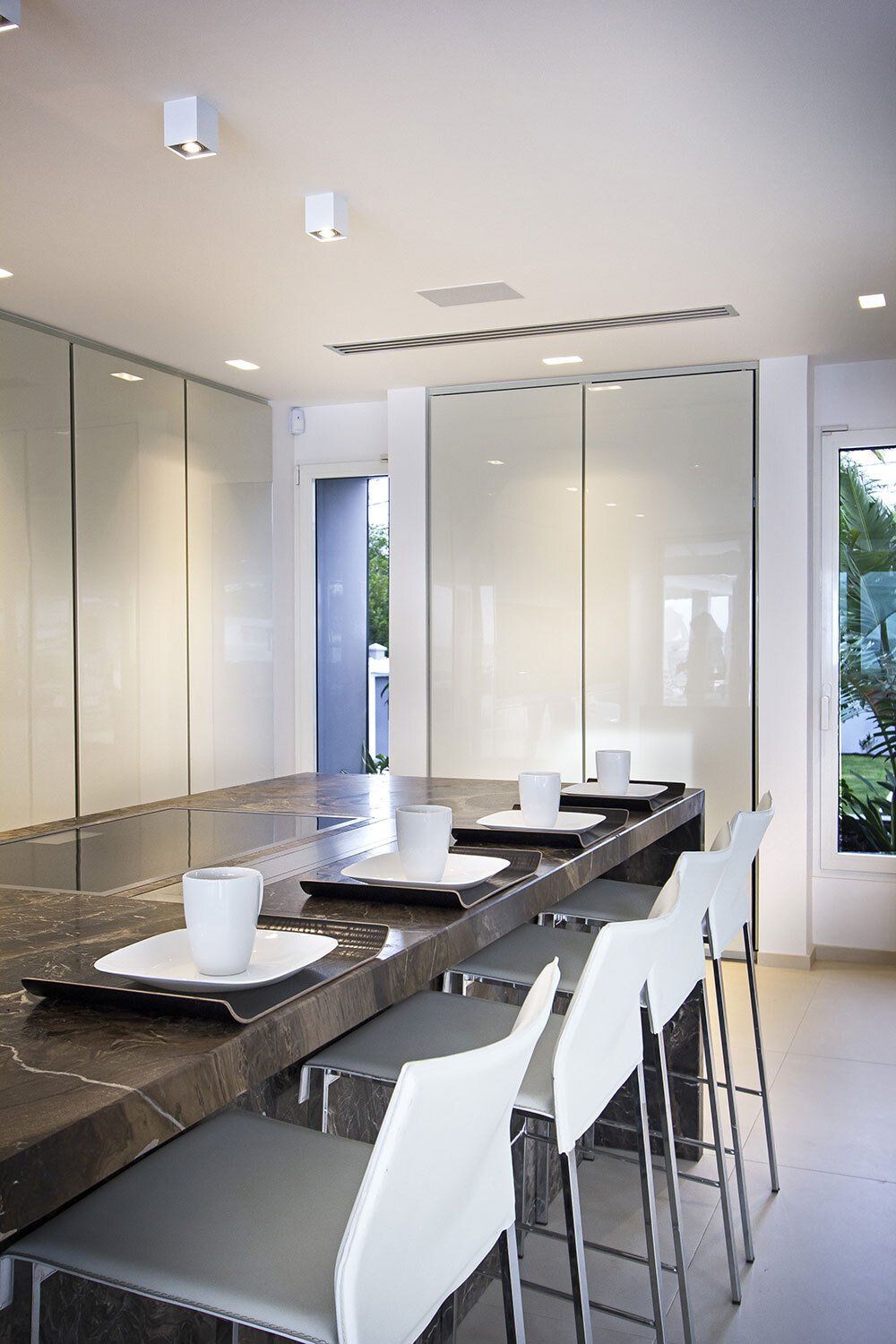 A kitchen with a long table and chairs and plates on it