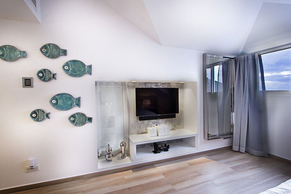 A living room with a flat screen tv and fish on the wall.
