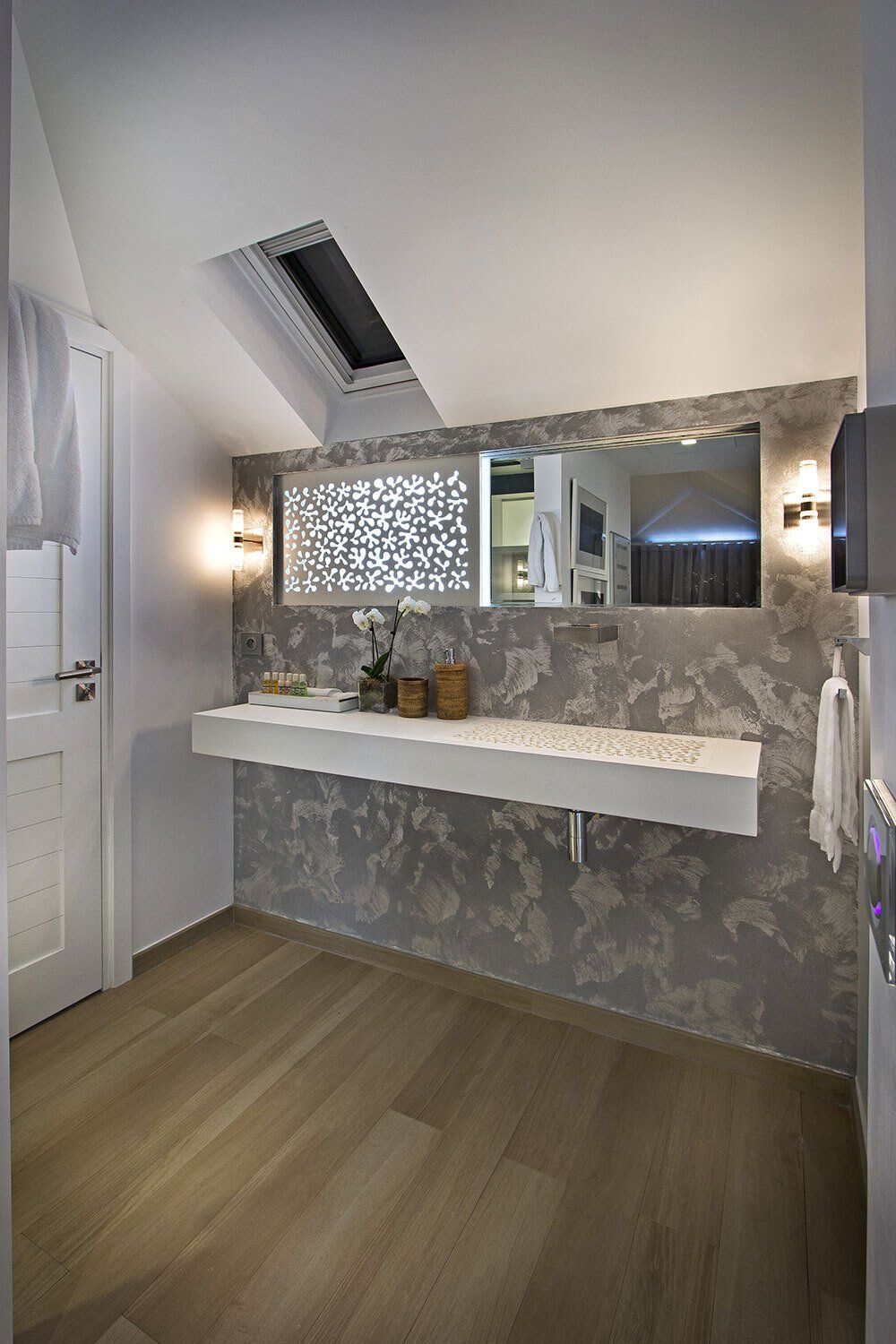 A bathroom with a sink , mirror and skylight.