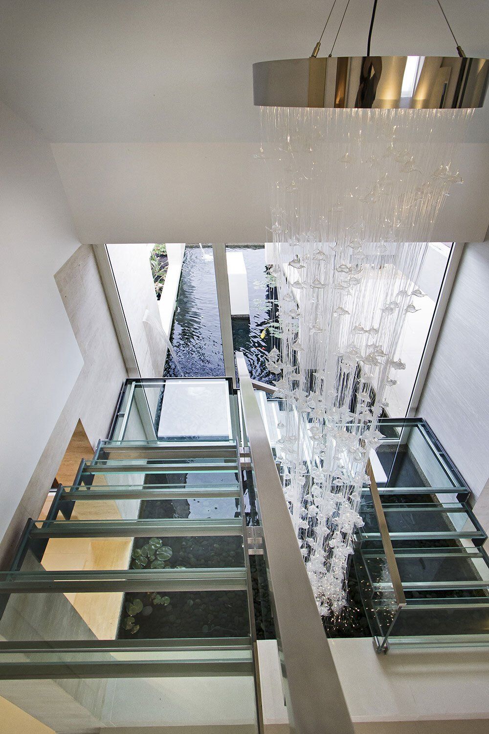 A glass staircase with a chandelier hanging from the ceiling
