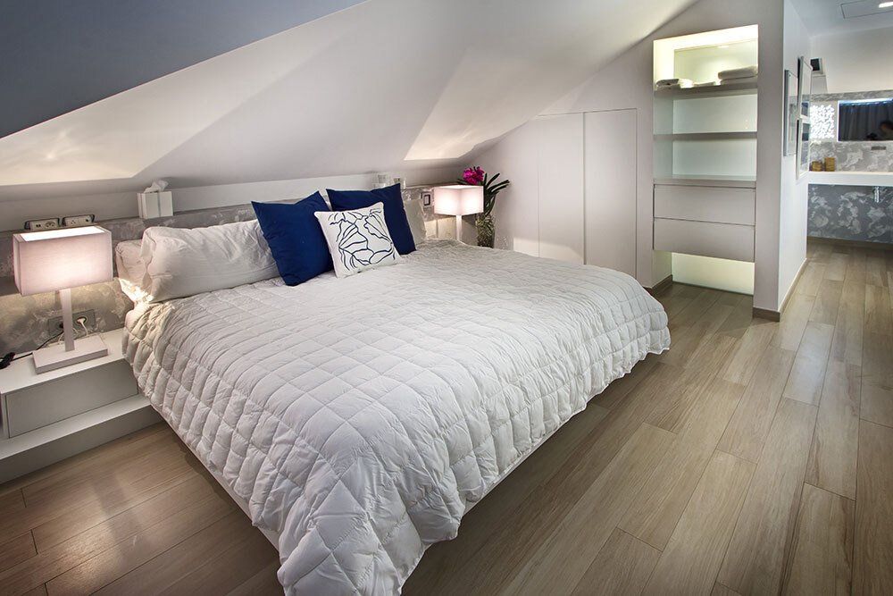 A bedroom with a white bed and blue pillows