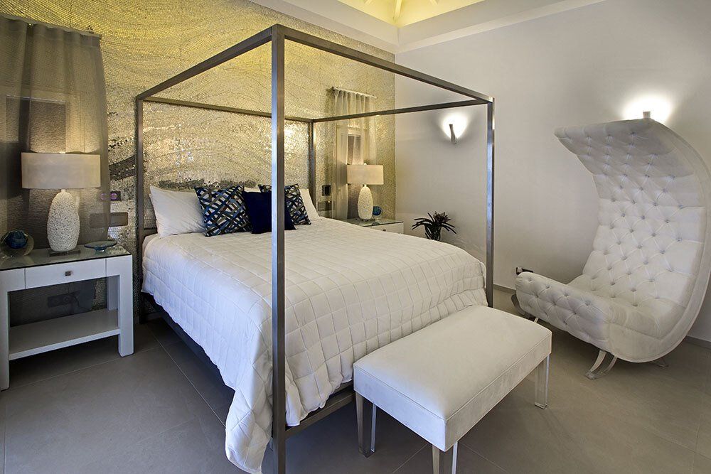 A bedroom with a four poster bed and a white chair