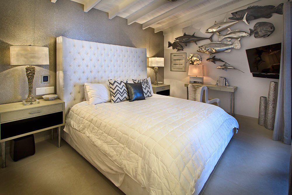 A bedroom with a large bed and fish on the wall